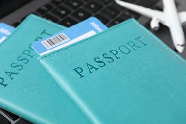 Pasaportlar, uçuş biletleri ve laptoptaki uçak modeli, yakın plan.