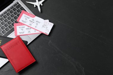 Pasaportlar, uçuş biletleri, uçak modeli ve siyah masadaki dizüstü bilgisayar, düz konum. Metin için boşluk