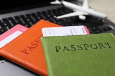 Pasaportlar, uçuş biletleri, uçak modeli ve dizüstü bilgisayar masada, yakın plan.