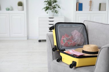 İçinde farklı kıyafetler, şapka ve pasaport bulunan bavulu açık tut. Metin için boşluk