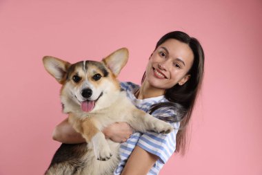 Hayvan eğitimi. Pembe arka planda sevimli köpeği olan bir kadın.