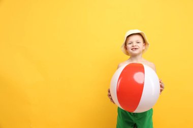 Teninde güneş kremi ve sarı arka planda şişme top olan küçük çocuk, mesaj için yer var.