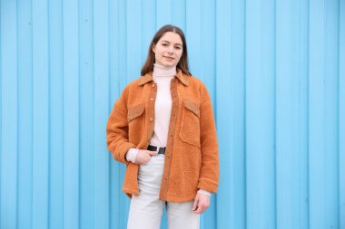 Açık mavi duvarın yanında güzel bir genç kızın portresi