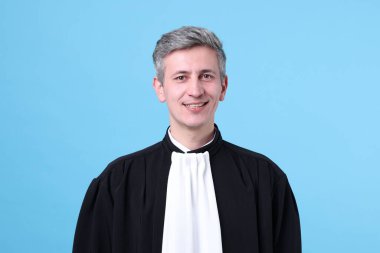 Açık mavi arkaplanda gülümseyen yargıç portresi