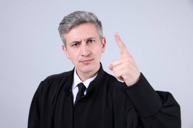 Gri arka planda parmak sallayan yargıcın portresi