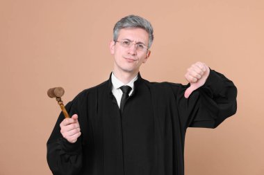 Bej arkaplanda başparmak gösteren tokmakla hakim