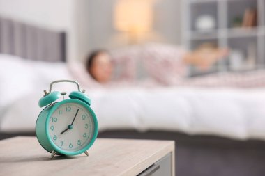 Evde yatakta egzersiz yapan genç bir kadın. Çalar saate odaklan. Sabah rutini