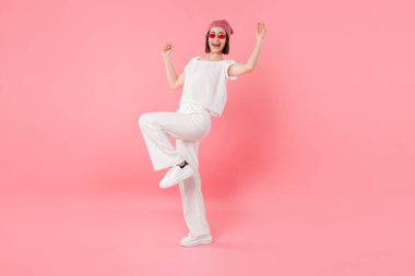 Bandanalı mutlu kadın pembe arka planda dans ediyor