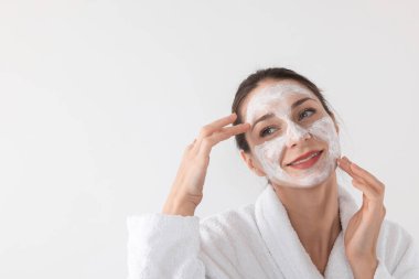 Spa günü. Beyaz arka planda yüzüne maske takan güzel bir kadın. Mesaj için boşluk.