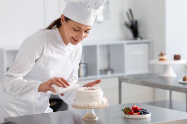 Bir şişe soslu şekerlemeci mutfakta pasta yapıyor.