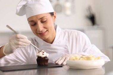 Şekerci, mutfakta çikolata parçalarıyla kek süslüyor.