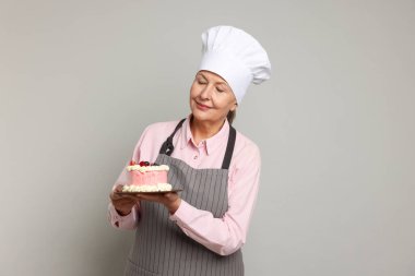 Açık gri arka planda pastası olan profesyonel bir pastacı.