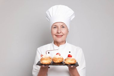 Açık gri arka planı olan profesyonel pasta şefi.