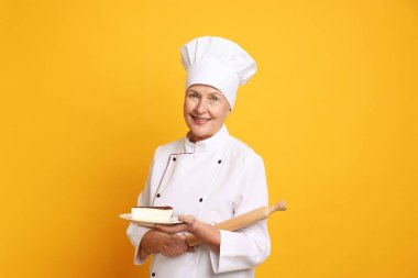 Turuncu arka planda bir parça kek ve oklavayla profesyonel pasta şefi.