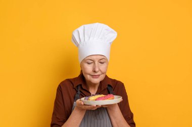 Turuncu arka planda eklerleri olan profesyonel bir şekerci.