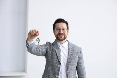 Emlakçının elinde ev şeklindeki anahtarlık var.