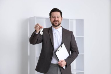 Emlakçının elinde evin anahtarı, anahtarlık ve pano var.