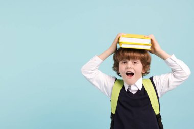 Sırt çantası ve açık mavi arkaplan kitapları olan sevimli bir okul çocuğu.