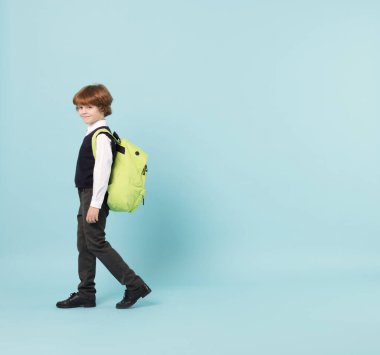 Açık mavi arka planda sırt çantası olan sevimli okul çocuğu, mesaj için yer var.