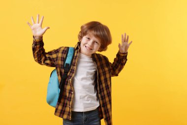 Turuncu arka planda sırt çantası olan tatlı bir okul çocuğu.