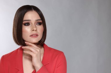 Açık gri arka planda muhteşem düz saçları olan güzel bir genç kadının portresi.