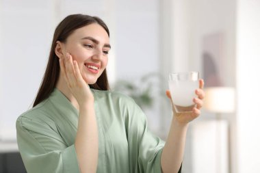 Arka planda bir bardak kolajen suyu olan gülümseyen kadın.