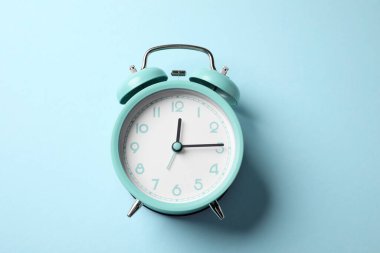 Açık mavi arkaplanda turkuaz alarm saati, üst görünüm