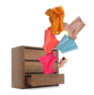 Giysiler beyaz arka planda şifoniyerden uçuyor.