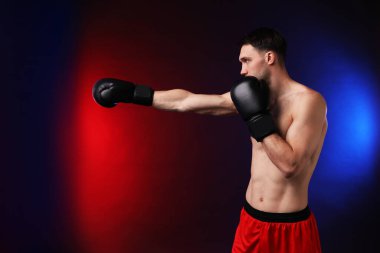 Boks eldivenli bir adam neon ışıklarıyla arka planda savaşıyor.