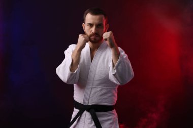 Üniformalı bir adam renkli ışıklarla ve dumanla karate yapıyor.