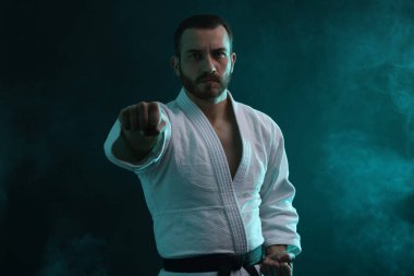 Renkli ışıklar ve duman içinde üniforma giyen bir karateci.