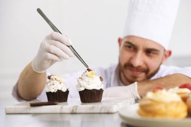 Şekerci, lezzetli kekler yapıyor. Mutfaktaki masada çikolata traşlı. Seçici bir odak noktası.