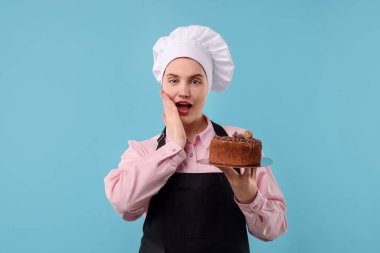 Açık mavi arka planda lezzetli çikolatalı pasta yapan bir pastacı.