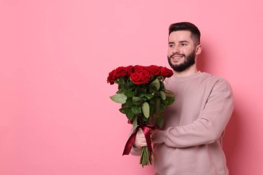 Pembe arka planda kırmızı gül buketi olan mutlu adam, mesaj için yer.