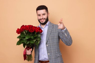 Bej arka planda kırmızı gül buketi olan mutlu adam.