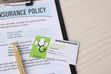 Sağlık sigortası kartı, poliçe ve kalem beyaz tahta masa, yakın plan.