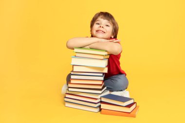 Turuncu arka plan hakkında çok farklı kitapları olan bir çocuk.