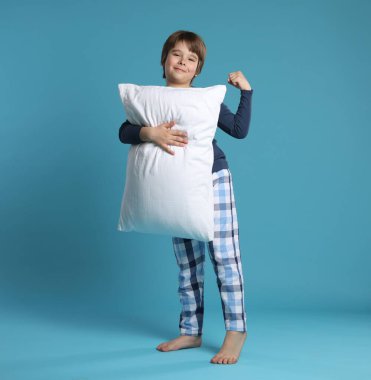 Açık mavi arka planda yastığı olan sevimli bir çocuk.