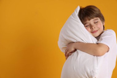 Turuncu arka planda yastığı olan tatlı bir çocuk. Metin için boşluk