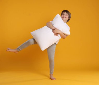 Turuncu arka planda yastığı olan tatlı bir çocuk.