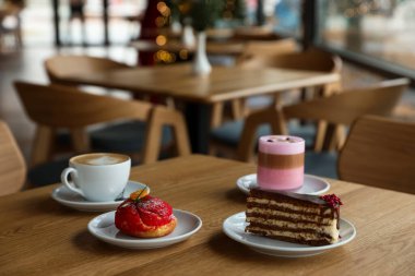 Kafedeki ahşap masada servis edilen aromalı kahve ve lezzetli tatlılar.
