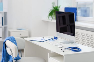 Masasında steteskop, evrak ve bilgisayar olan doktorun iş yeri