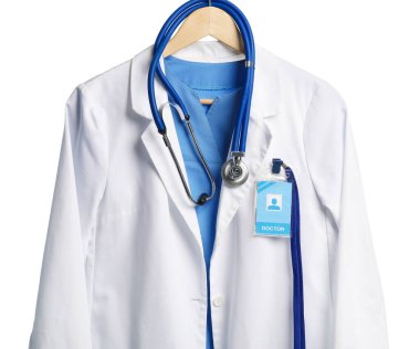 Beyaz arka planda asılı steteskop ve rozetli doktorun ceketi.