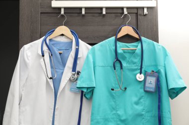 İçerideki askılarda steteskoplu ve rozetli sağlık görevlileri üniformaları.