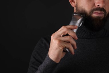 Siyah arka planda sakal kesen adam, yakın plan. Metin için boşluk