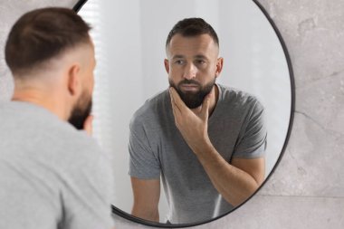 Banyoda aynanın yanındaki yakışıklı sakallı adam.