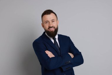 Gri arka planda takım elbiseli yakışıklı sakallı adam.