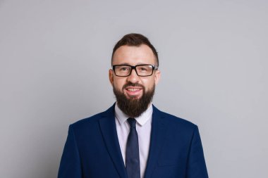 Gri arka planda takım elbiseli yakışıklı sakallı adam.