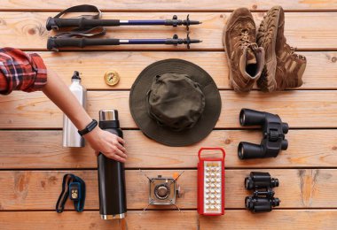 Ahşap masada farklı yürüyüş ekipmanları ve aletleri olan bir kadın.
