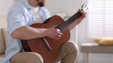 Evde gitar çalan adam, yakın plan. Rahatlatıcı hobi